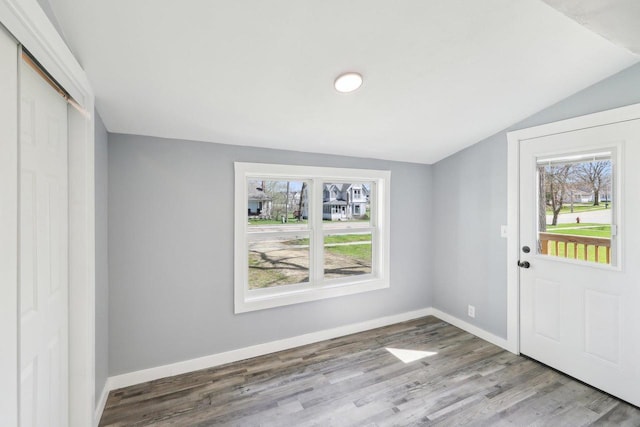 foyer with baseboards, lofted ceiling, and wood finished floors