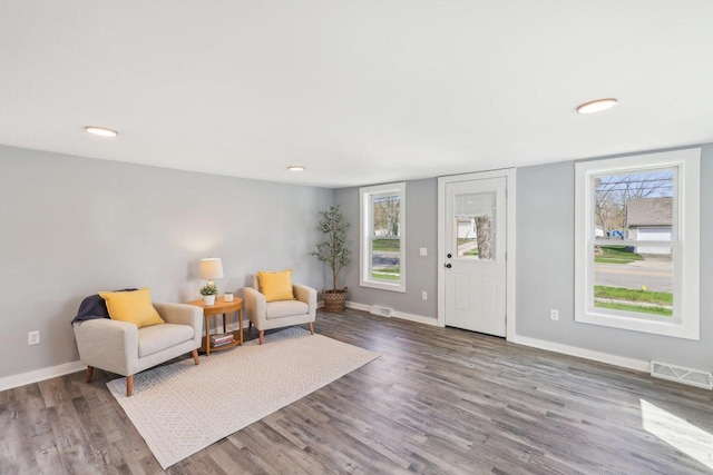 sitting room featuring visible vents, baseboards, wood finished floors, and a healthy amount of sunlight
