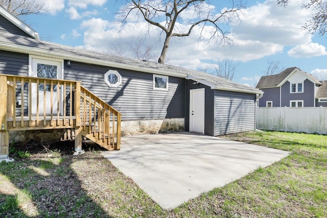 back of property featuring fence, an outdoor structure, a storage unit, a yard, and a patio