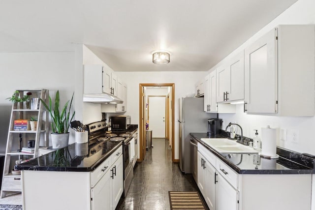 kitchen with white cabinetry, a sink, appliances with stainless steel finishes, dark countertops, and under cabinet range hood