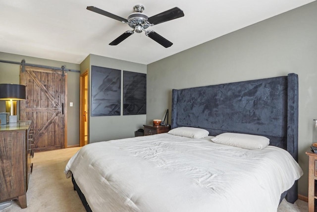 carpeted bedroom featuring a barn door and a ceiling fan