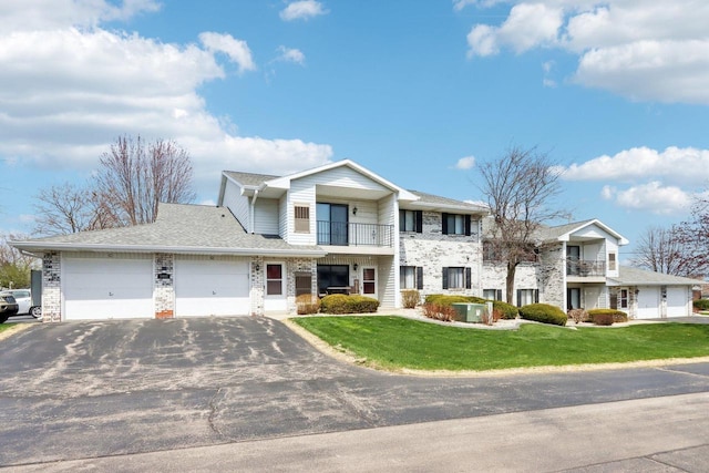 view of front of house featuring aphalt driveway, a balcony, a front yard, and an attached garage