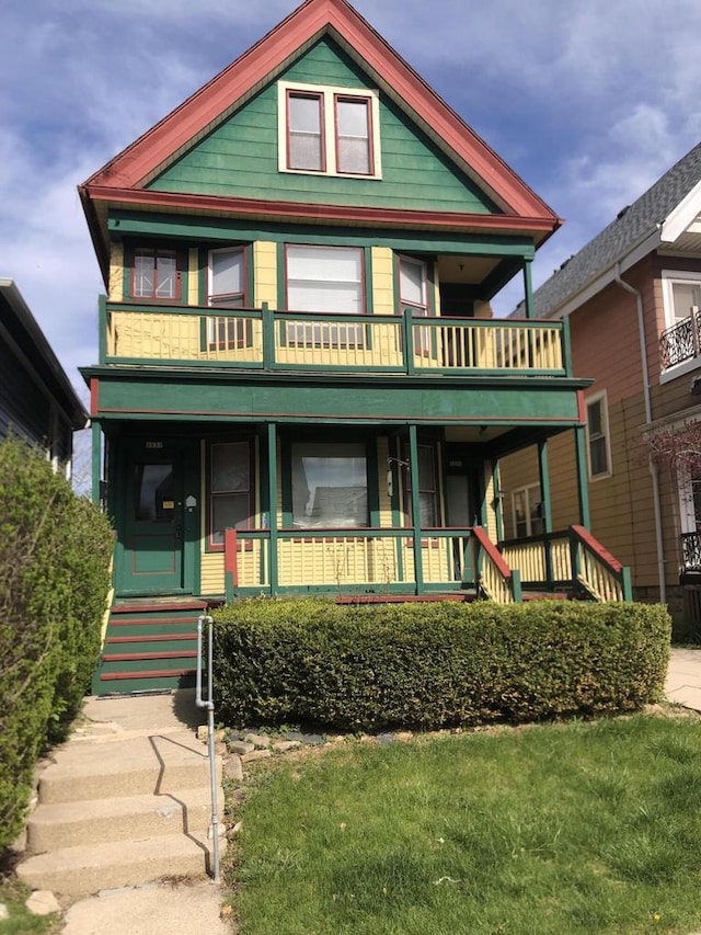 victorian-style house with covered porch, a front lawn, and a balcony