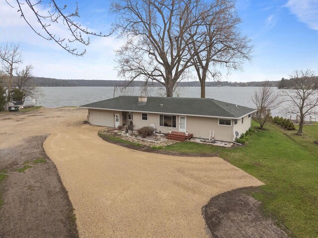 W2138 Melmar Dr, Markesan, WI 53946 - back of property with a chimney, a water view, a garage, dirt driveway, and a lawn