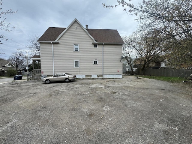view of side of home featuring a shingled roof and fence