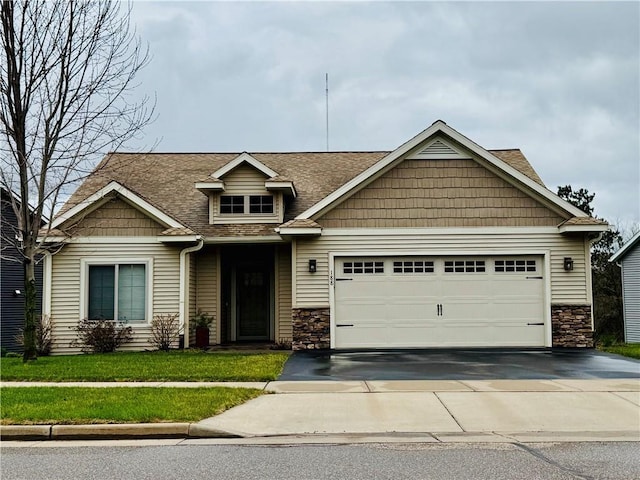 craftsman-style home with stone siding, concrete driveway, a garage, and a shingled roof