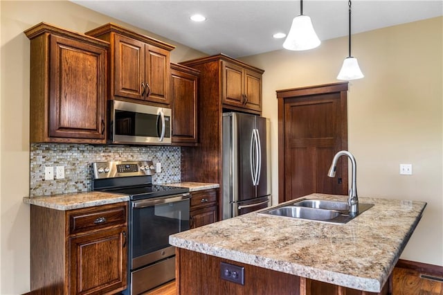 kitchen featuring appliances with stainless steel finishes, a sink, light countertops, wood finished floors, and tasteful backsplash