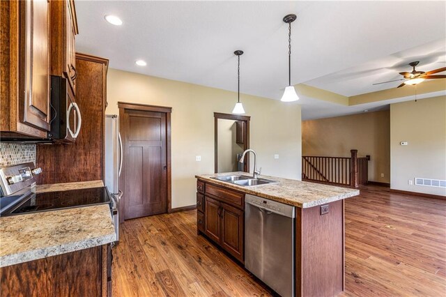 kitchen with stainless steel appliances, a sink, light wood-style floors, baseboards, and light countertops