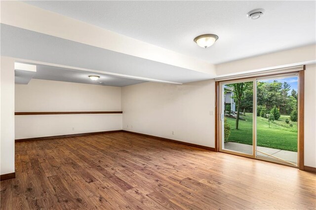 unfurnished room featuring baseboards, wood finished floors, and a smoke detector