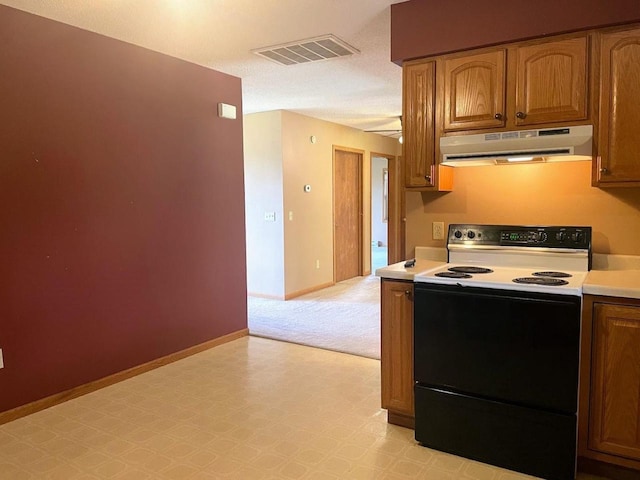 kitchen featuring under cabinet range hood, visible vents, baseboards, light countertops, and electric range