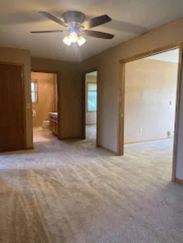 unfurnished bedroom with carpet flooring, baseboards, ceiling fan, and ensuite bath