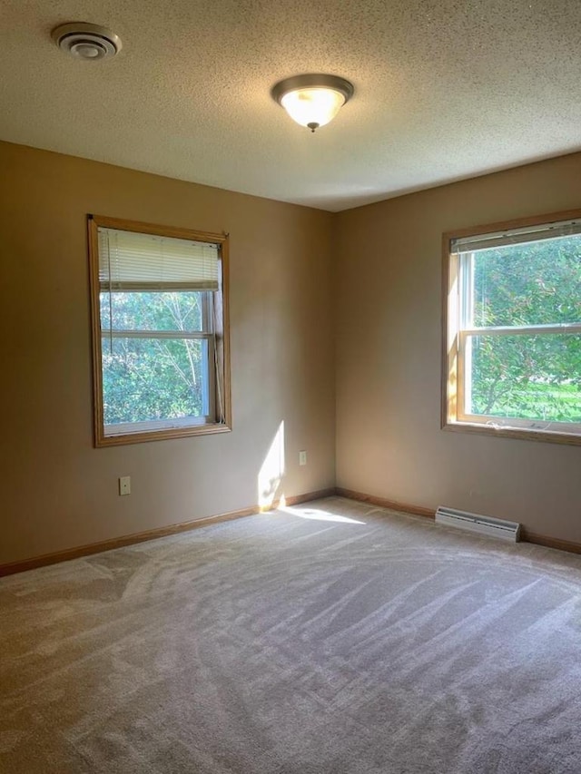 empty room with baseboard heating, visible vents, a textured ceiling, and carpet flooring