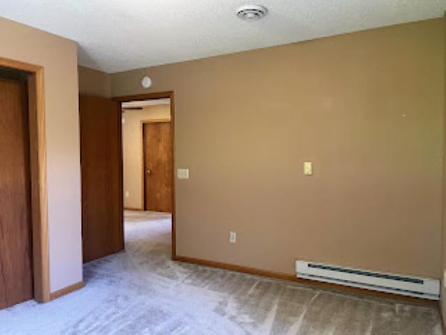 unfurnished room with a baseboard radiator, visible vents, light colored carpet, and baseboards