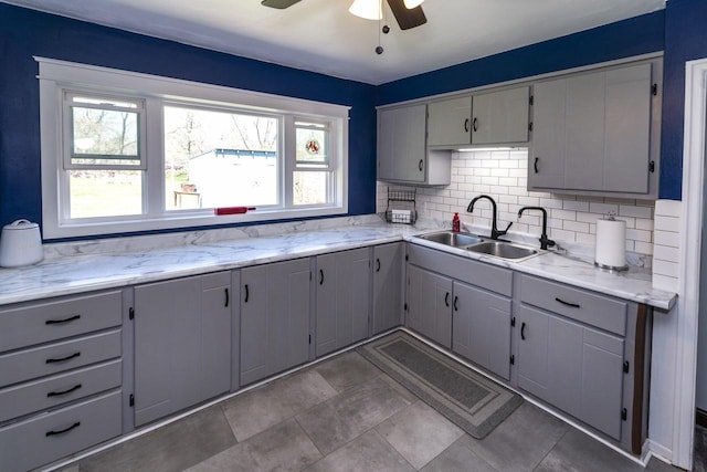 kitchen with a sink, backsplash, and gray cabinets