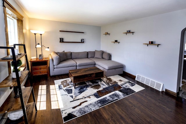 living room with wood finished floors, visible vents, and baseboards