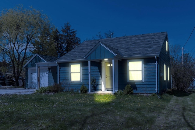 view of front of home featuring roof with shingles, board and batten siding, a front yard, and an attached garage