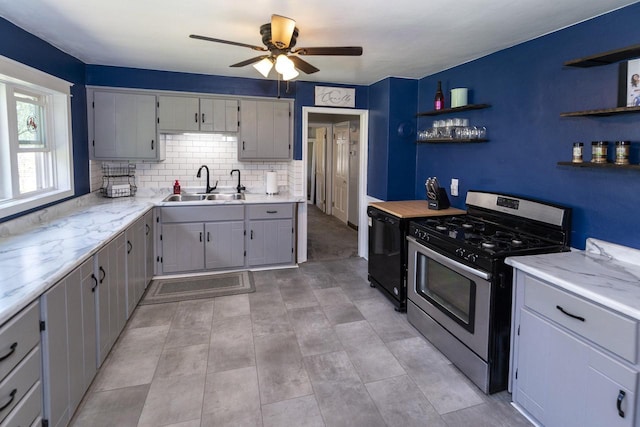 kitchen featuring gray cabinets, stainless steel gas range, open shelves, and a sink