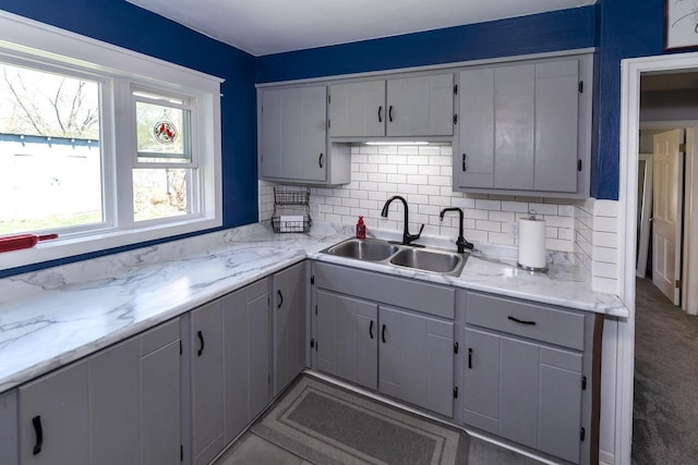 kitchen with decorative backsplash, gray cabinets, and a sink