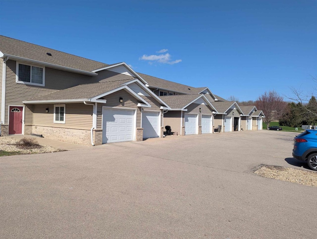 townhome / multi-family property featuring community garages and roof with shingles