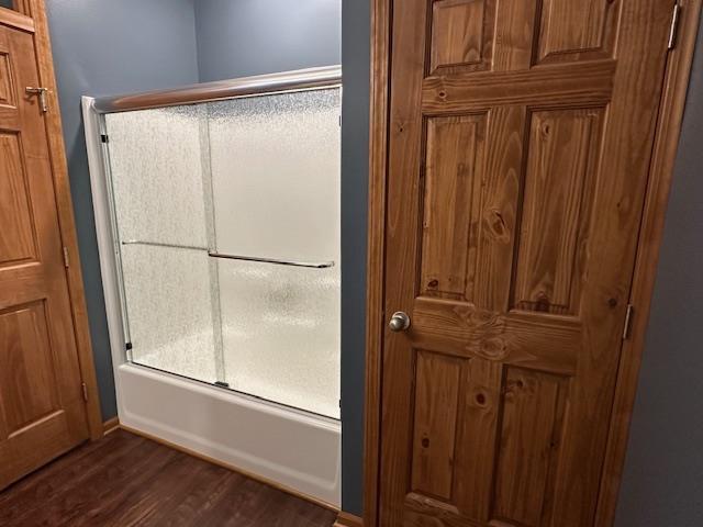 bathroom with shower / bath combination with glass door and wood finished floors