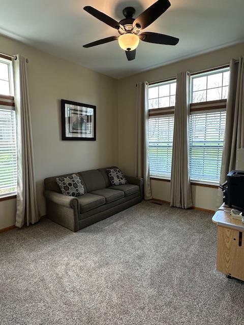 living room with baseboards, a ceiling fan, and carpet