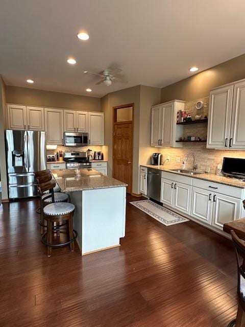 kitchen featuring ceiling fan, appliances with stainless steel finishes, a sink, backsplash, and dark wood-style floors