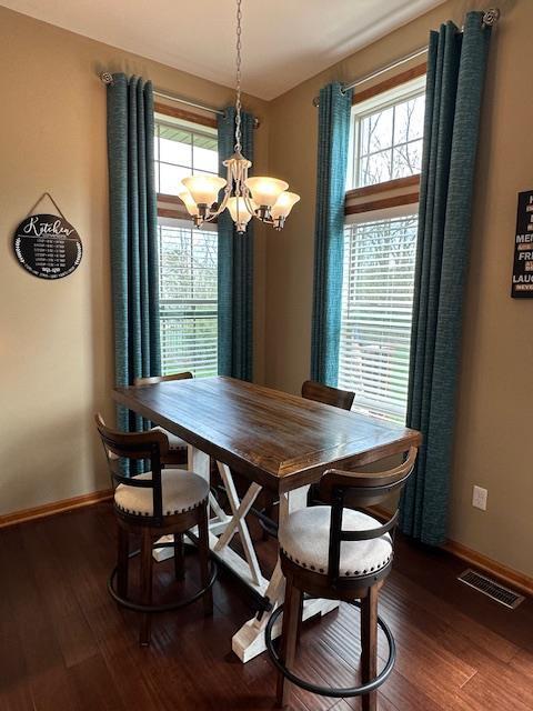 dining room featuring visible vents, baseboards, wood finished floors, and an inviting chandelier