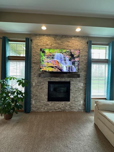 carpeted living area featuring recessed lighting and a stone fireplace