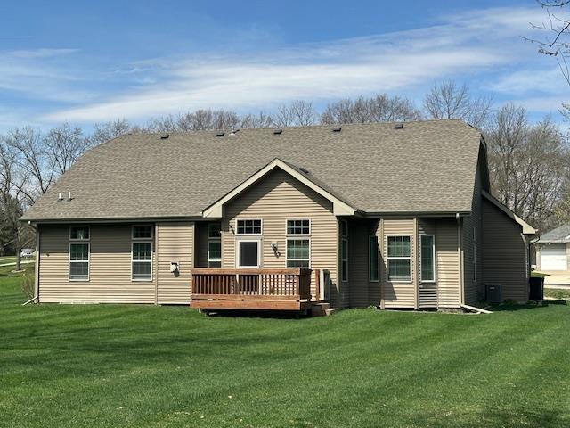 rear view of house with a yard, a deck, and roof with shingles
