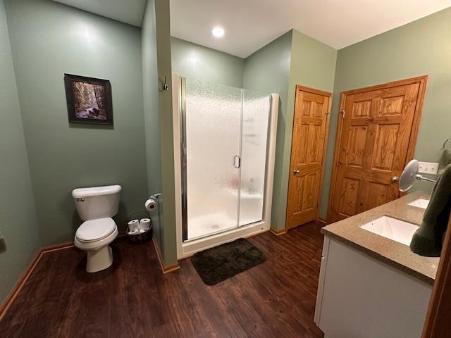 full bath with a shower stall, wood finished floors, vanity, baseboards, and toilet