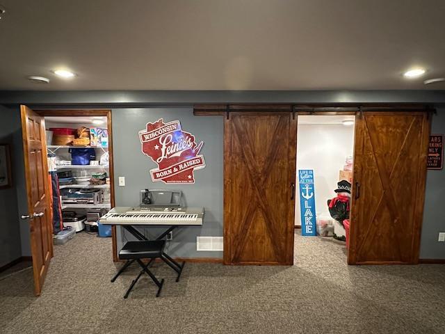 carpeted office space featuring recessed lighting and a barn door