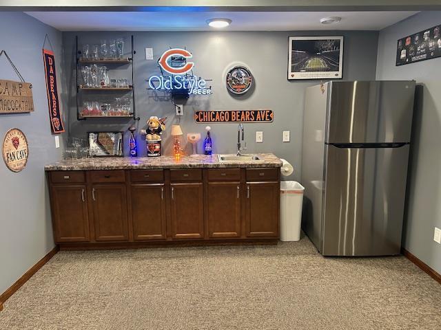 bar with freestanding refrigerator, baseboards, light colored carpet, a bar, and a sink