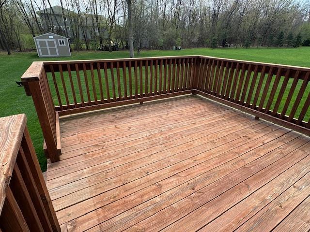 deck featuring a storage unit, an outdoor structure, and a yard