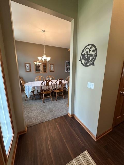 dining room featuring dark wood-style flooring, baseboards, and a notable chandelier