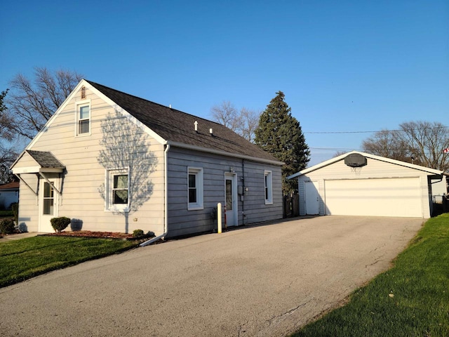 view of side of home featuring an outdoor structure, a yard, a garage, and a shingled roof