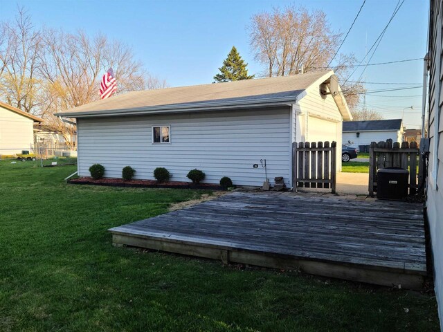 wooden terrace featuring fence, a yard, and an outbuilding