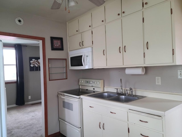 kitchen with white appliances, light countertops, carpet, a sink, and baseboards