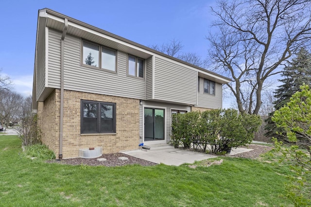 rear view of house featuring a lawn and brick siding