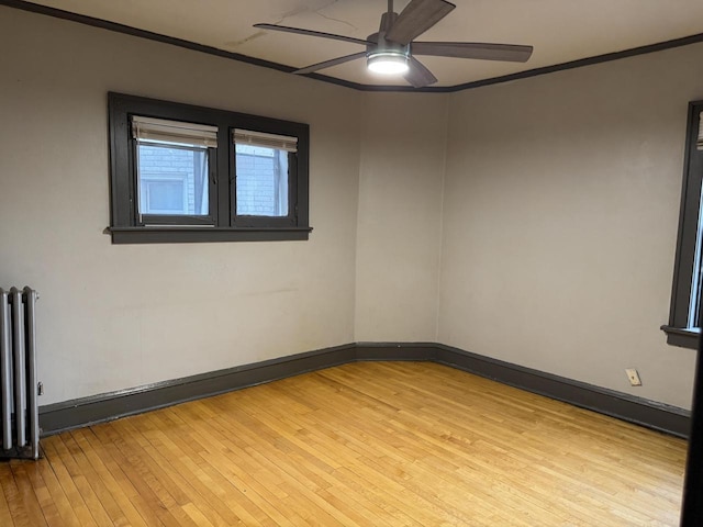 empty room featuring crown molding, ceiling fan, radiator heating unit, and light wood-style floors