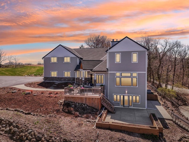 5400 N State Road 83, Hartland, WI 53029 - back of house at dusk with a wooden deck, a chimney, stairway, and a patio