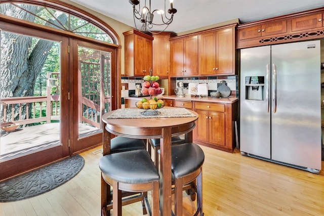 172 N St, Sun Prairie, WI 53590 - kitchen with stainless steel fridge, light wood-type flooring, brown cabinetry, and decorative backsplash