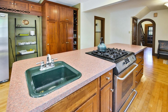 172 N St, Sun Prairie, WI 53590 - kitchen with stainless steel appliances, a sink, light wood finished floors, and brown cabinets
