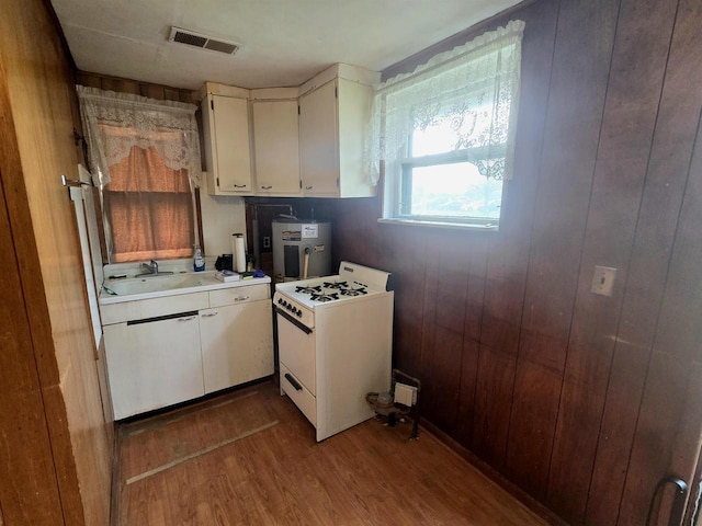 kitchen with visible vents, wood finished floors, white gas stove, light countertops, and white cabinetry