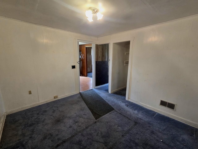 empty room featuring baseboards, visible vents, and dark colored carpet