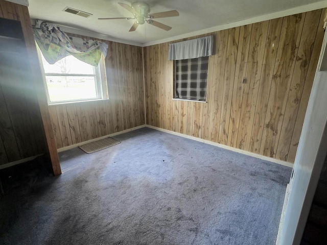 empty room featuring wooden walls, ceiling fan, baseboards, and carpet