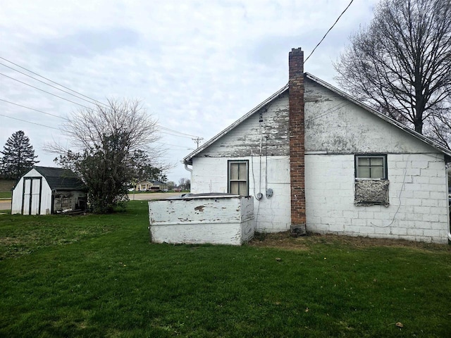 view of side of property featuring a lawn, a storage unit, an outdoor structure, and a chimney