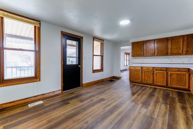 kitchen with visible vents, light countertops, baseboards, dark wood finished floors, and brown cabinetry