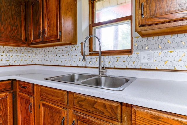kitchen with backsplash, light countertops, and a sink