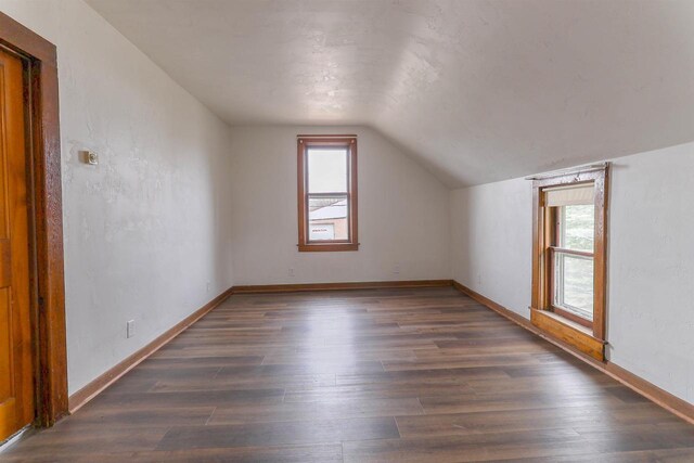 bonus room with dark wood-style flooring, plenty of natural light, and vaulted ceiling