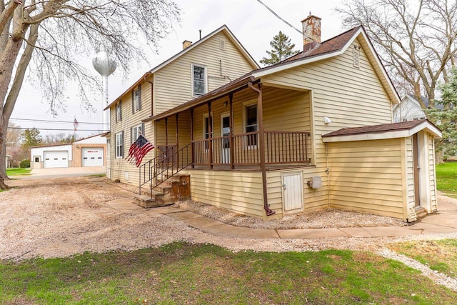 view of front of home with a porch, an outbuilding, and a chimney